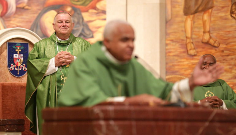 Archbishop Thomas Wenski of Miami listens as Father Jean Gaetan Louis Boursiquot, spiritual director of the Haitian ministry for the Orlando Diocese, speaks during Mass July 2 at St. James Cathedral. The Mass took place during the Convocation of Catholic Leaders in Orlando.