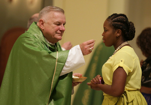 Archbishop Thomas Wenski of Miami serves Holy Communion during a Haitian Mass July 2 at St. James Cathedral during the Convocation of Catholic Leaders in Orlando.