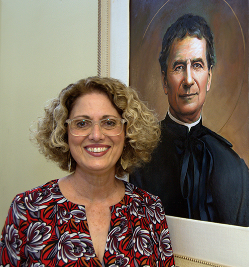 Berta Cabrera, executive director of St. John Bosco Clinic, shows a painting of the 19th century Italian saint.