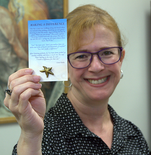 Luz Gallardo, supervisora de la Clínica San Juan Bosco, muestra un botoncito con una estrella de mar que se les entrega a todos los voluntarios de la clínica. La parábola de las estrellas de mar ilustra cómo una persona, aunque no pueda resolver un problema, aún puede hacer una diferencia.