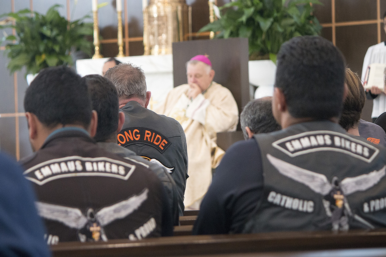 El Arzobispo Thomas Wenski, miembros del equipo de filmaci&oacute;n de "Long Ride Home" y los motociclistas de Ema&uacute;s de la iglesia Our Lady of Guadalupe oran despu&eacute;s de la comuni&oacute;n en la Misa del 5 de agosto.