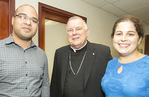 Archbishop Thomas Wenski poses with Catholic Legal Services' attorneys Felix Montañez and Kristie-Anne Padron during a visit to the agency's downtown office Sept. 27 to kick off the Share the Journey campaign.