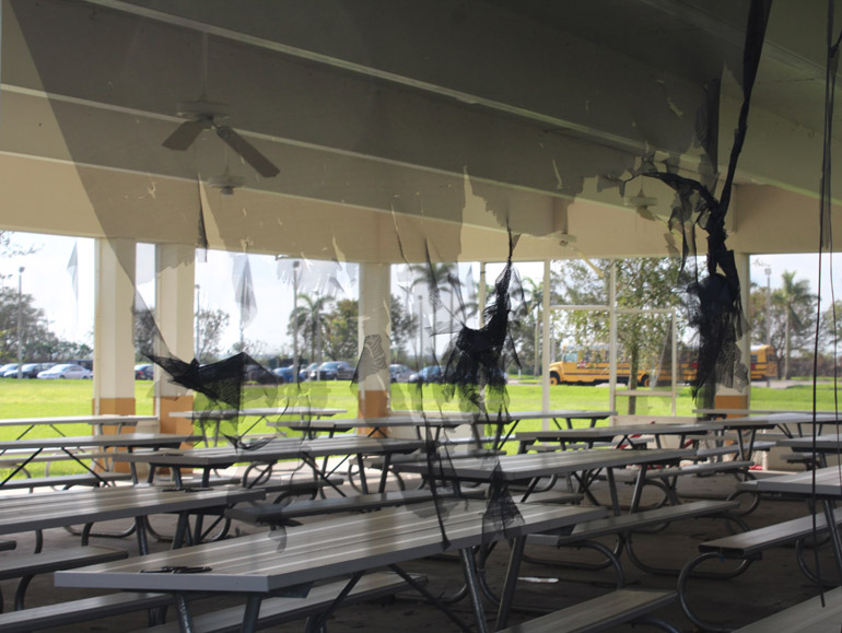 Shredded screen windows and doors, as well as dangling ceiling fans, provide an eerie ambience to the outdoor dining pavilion where many students eat lunch.