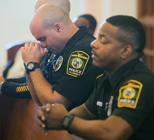 Miami Gardens police officers Carlos Austin, left, and Kevin Yearby pray during the Blue Mass.