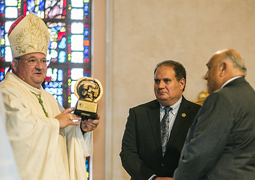 Bishop Peter Baldacchino holds up the plaque of appreciation he received from John Rivera, far right, president of the Miami-Dade Police Benevolent Association, and Mark Alfieri.