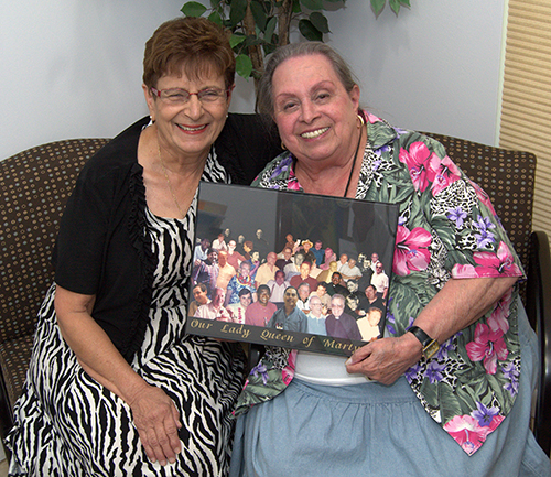 Regina Medina, left, and Jessie Chiccone hold a composite photo of former pastors at Our Lady Queen of Martyrs. The two women met four decades ago, and "We've been huggers ever since," Chiccone said.