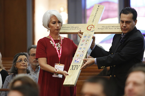 Ana García y Manuel Pelaez llevan la cruz del V Encuentro hacia el altar durante la  Misa de apertura de la celebración arquidiocesana del Encuentro, celebrada el 7 de octubre en la iglesia de la Inmaculada Concepción en Hialeah.