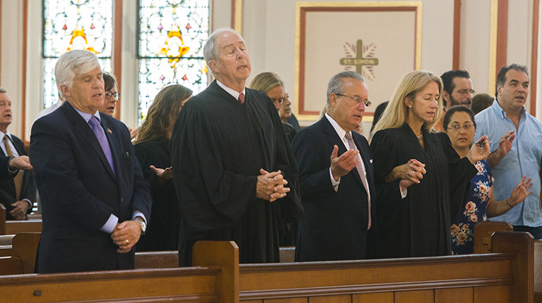 From left: Judge Federico Moreno, Judge Vance Salter, and George Mencio, with his wife, Judge Cecilia Altonaga, pray the Our Father during the Red Mass.