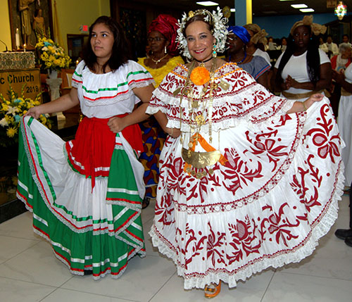 Two St. Helen parishioners process in traditional outfits during the kickoff Mass for its 50th anniversary. From left are Raquel Zacarias, representing Mexico, and Wendy Silva, representing Panama.