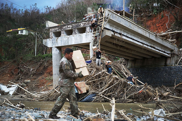 Members of the U.S. Army 1st Special Forces Command deliver boxes of M.R.E's and water up a makeshift ladder to people that were cut off after the bridge collapsed when Hurricane Maria swept through the island on October 5, 2017 in Utuado, Puerto Rico. The neighborhood was cut off from help for about 2 weeks and there is still a need for basic life necessities after the category 4 hurricane passed through.