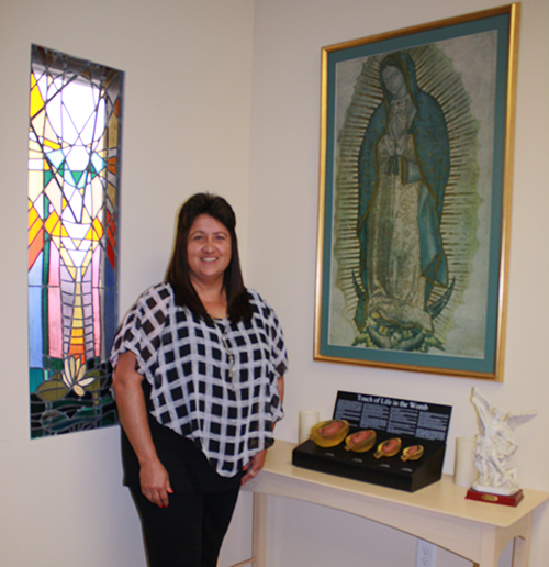 Archdiocese of Miami Respect Life Ministry Education Coordinator Sandi Le Bel poses for a photo in front of fetal models, which are used to show pregnant moms the various stages of their unborn child's development.