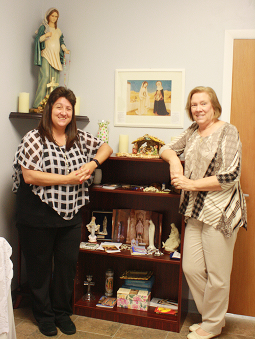 Archdiocese of Miami Respect Life Ministry Education Coordinator Sandi Le Bel and Director Joan Crown pose in front of pro-life figures: a picture of "The Visitation" and the statue of Our Lady of Hope Expectant, the namesake of the Respect Life office on Hollywood Boulevard in Hollywood.
