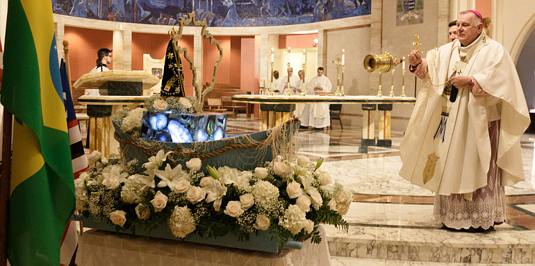 Miami Archbishop Thomas Wenski incenses the pilgrim image of Our Lady of Aparecida, Brazil’s national patroness, during an Oct. 8 celebration and Mass at St. Mary’s Cathedral. At left is the furled flag of Brazil.