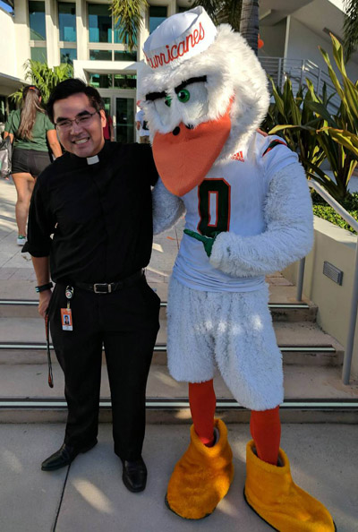 Aquí está Sebastián: El P. Phillip Tran posa con la mascota ibis de la Universidad de Miami, Sebastián. El P. Tran, es el nuevo capellán católico en la universidad, está haciendo un esfuerzo para asistir a la mayor cantidad posible de eventos deportivos y sociales en todo el campus.