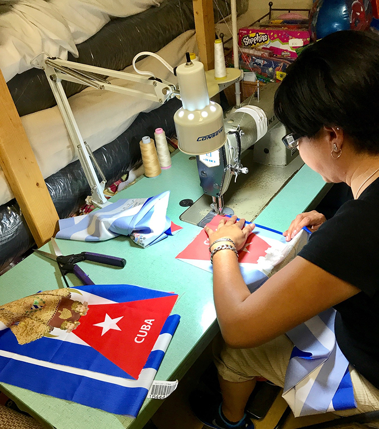 Lucia Vallejo, encargada y maestra del taller de costura del Centro La Salle, en Homestead cose las estolas con la imagen de la Virgen de la Caridad sobre la bandera cubana.