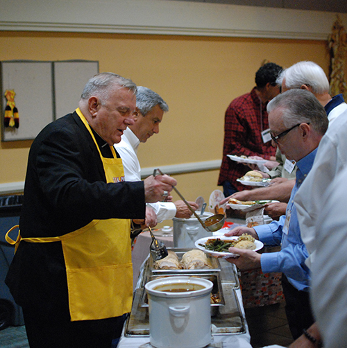 Archbishop Thomas Wenski helps serve Thanksgiving dinner to members of St. John Neumann's Men's Club Nov. 6.