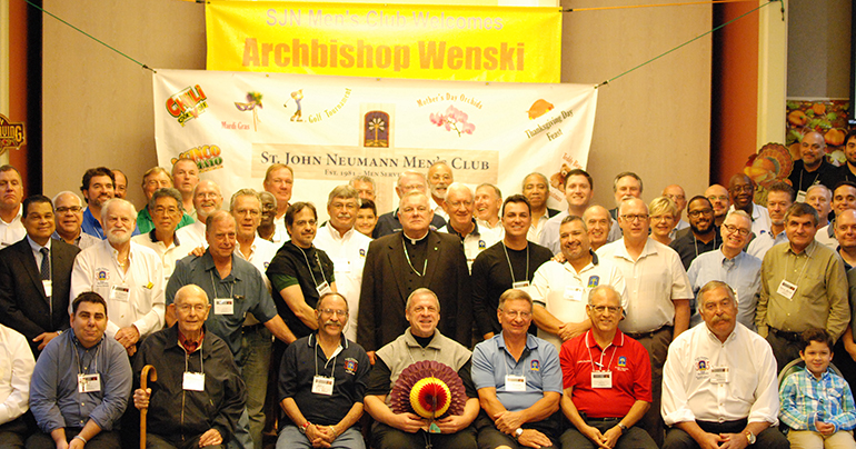 Archbishop Thomas Wenski poses for a picture with members of St. John Neumann's Men's Club during a visit Nov. 6. Seated underneath the archbishop is St. John Neumann's pastor, Father Pablo Navarro.