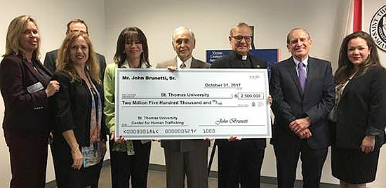 John Brunetti, center, shows the check he donated to the Human Trafficking Academy at St. Thomas University. To the right of Brunetti is Msgr. Franklyn Casale, president of the university.