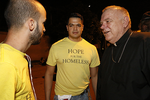 Archbishop Thomas Wenski chats with Hope for the Homeless co-founder Moises Pineda, center, and fellow volunteer Michael Perez. The group, formed at St. Agatha Church, go out and feed the homeless every Wednesday evening.