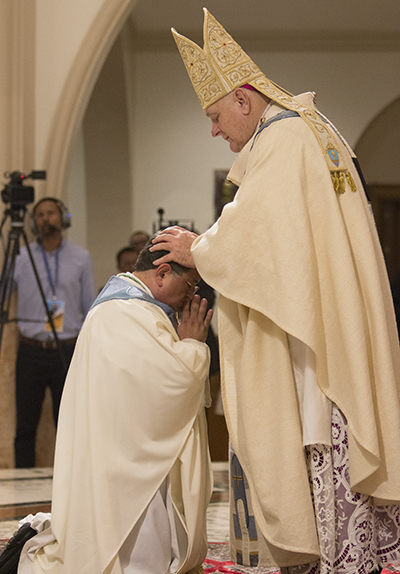 El Arzobispo Thomas Wenski pone las manos sobre el P. Enrique Delgado, llamando al Espíritu Santo y en ese momento lo ordena Obispo.