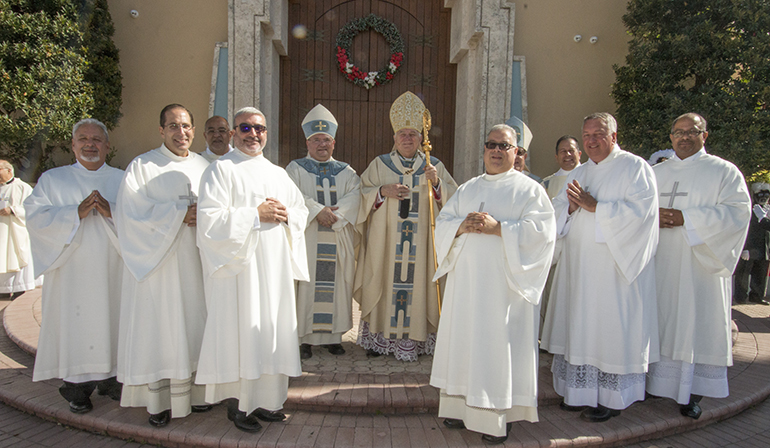 The newly ordained deacons pose outside the cathedral after the ceremony with Archbishop Thomas Wenski, center, Bishop Peter Baldacchino, center left, and Archbishop Emeritus John C. Favalora (rear right). From left, front row: Deacon Ricardo Rauseo, Deacon Sergio Rodicio, Deacon Jorge Reyes, Deacon William Bertot, Deacon Thomas Ermer and Deacon David Bowen. Behind them, at left, is Deacon Victor Pimentel, director of the Office of Permanent Diaconate, and at right, Deacon Frank Gonzalez, who proclaimed the Gospel.