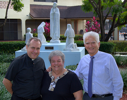 El P. José Álvarez, párroco de Our Lady of the Lakes, posa al lado de la estatua de la escuela, la Virgen de Fátima, junto con la maestra de kindergarten, Irma Tejeda; y el director, Ricardo Briz.