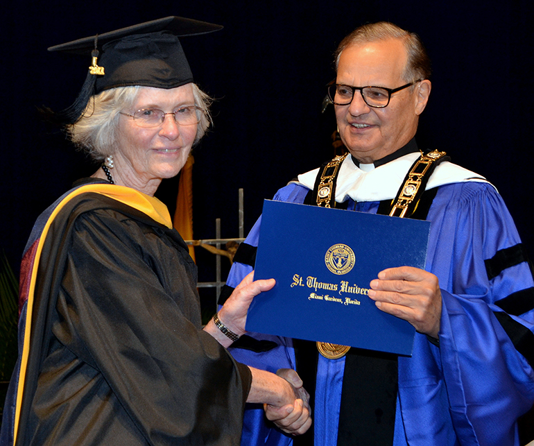 Dr. Mary Jo O'Sullivan receives her diploma in bioethics Dec. 16 from Msgr. Franklyn Casale, president of St. Thomas University.