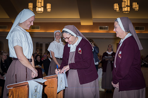 Sister Mary Rachel Hart smiles as Sister Ana Margarita Lanzas, the community's vicar, signs the Formula of Profession, and Mother Adela Galindo, superior and foundress, looks on.