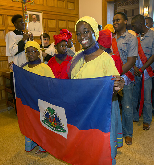 Laurie Bruno, holding flag in foreground, and other members of the Haitian Apostolate, prepare to walk in the procession at the start of the Mass.