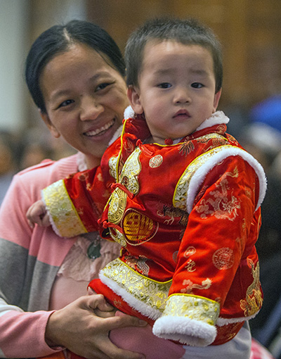 Jindie Lin of the Chinese Apostolate holds her son, Kenny jiang, 13 months old, during Mass.