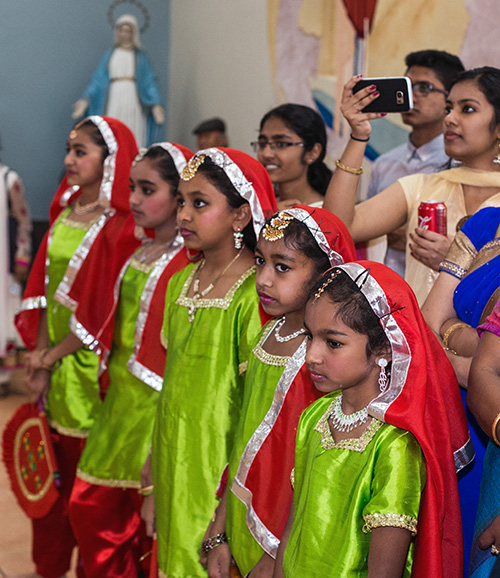 Jóvenes miembros del apostolado de la India se preparan para realizar un baile tradicional en la recepción que siguió a la Misa de Migración.