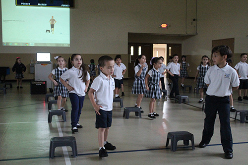 Los niños de kindergarten de la escuela Our Lady of the Lakes avanzan y retroceden durante los ejercicios matutinos de NeuroNet Learning.