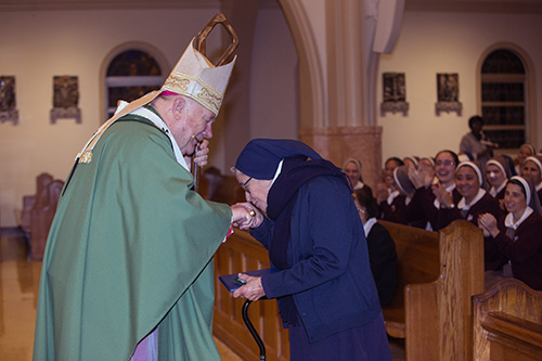 Sister Clemencia Fernandez kisses Archbishop Thomas Wenski's ring as she receives a gift for her 70 years in religious life. The annual celebration of the World Day of Consecrated Life took place Jan. 20 at St. Mary Cathedral.