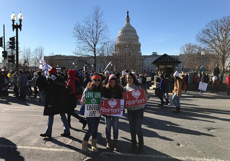 St. Thomas Aquinas seniors, from left, Paige Pokryfke, Shania Moscat, and Phoenix Tabasso pose with their pro-life placards in front of the U.S. Capitol as they take part in the March for Life Jan. 19, 2018.