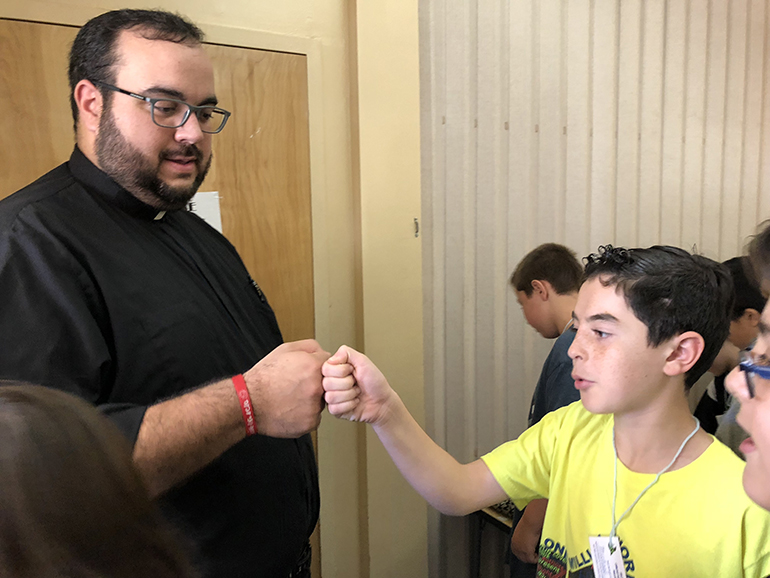 Deacon Matthew Gomez, currently in his final year of studies at St. Vincent de Paul Regional Seminary in Boynton Beach, bumps fists with a St. Bonaventure School fifth grader during their first meeting in December. The class has "adopted a seminarian" as part of their studies on the sacrament of Holy Orders.