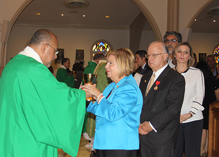 El diácono Victor Pimentel, director espiritual del movimiento Matrimonios en Victoria le da el vino a Beatriz Harriman, durante la Misa por el 20 aniversario del movimiento. Detrás de ella su esposo John Harriman.