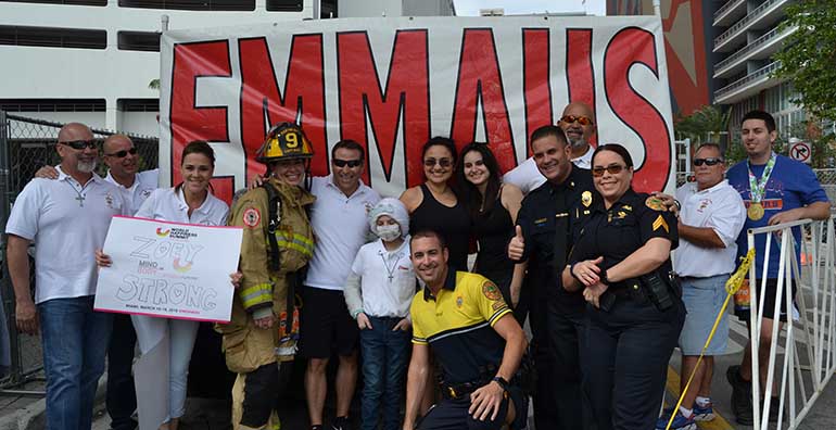 Members of Immaculate Conception's Emmaus groups, along with their children and firefighters and police from Hialeah and Miami, pose at the finish line with Immaculate fourth-grader Zoey Pavon, center, who is being treated for stage four neuroblastoma.