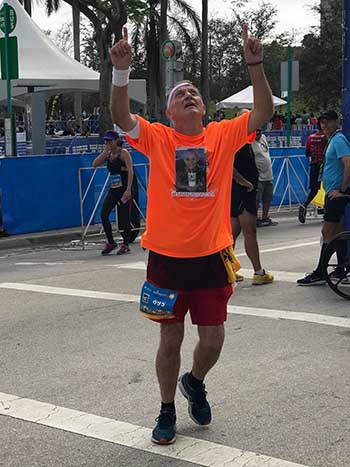 Immaculate Conception parishioner and Emmaus member Robert Hubbard thanks God after crossing the finish line of the 26.2-mile FitBit Miami Marathon. He's wearing Zoey Pavon's picture on his T-shirt.
