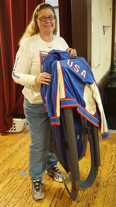 Toni Damigella poses with her luge sled and Olympic jacket.