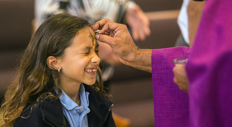 FOTO DE ARCHIVO: Brianna Puglisi, de 9 años, estudiante de segundo grado en la escuela St. Rose of Lima en Miami Shores, hace una mueca mientras el párroco de St. Rose, el P. George Packuvettithara, le marca la frente con cenizas durante la Misa del miércoles de ceniza el 14 de febrero de 2018.