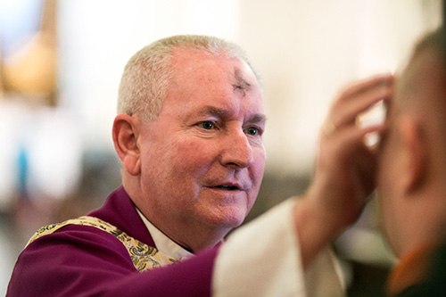 Marked with ashes himself, Father Michael Grady, pastor, imposes ashes on the faithful during Ash Wednesday Mass Feb. 14 at St. Anthony Church, Fort Lauderdale. Archbishop Thomas Wenski presided at the Mass.