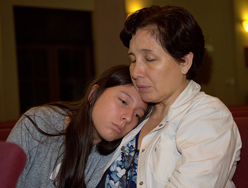 A mother and daughter pray at Mary Help of Christians Church, Parkland, during a service Feb. 15 for victims of the Feb. 14 shooting at a nearby high school.