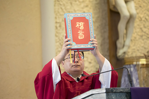 Father Thomas Liang, visiting priest from Shanxi Province in China, holds up the Book of the Gospels during the Chinese New Year Mass and Ancestral Veneration at St. Jerome Church in Fort Lauderdale. Mass was celebrated in Chinese.