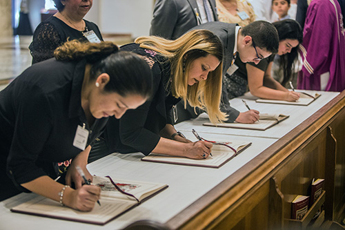 Catechumens sign the Book of the Elect during the Rite of Election ceremony Feb. 18. Archbishop Thomas Wenski accepted 447 catechumens as "elect," the final step before their full initiation into the Catholic Church, during two Rite of Election ceremonies held at St. Mary Cathedral Feb. 18.