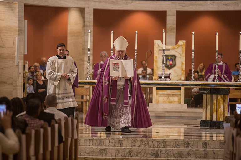 Archbishop Thomas Wenski walks through the cathedral holding up one of the books on which the "elect" have signed their names, indicating their desire to be baptized and become practicing members of the Catholic Church. Archbishop Wenski accepted 447 catechumens as "elect," the final step before their full initiation into the Catholic Church, during two Rite of Election ceremonies held at St. Mary Cathedral Feb. 18.