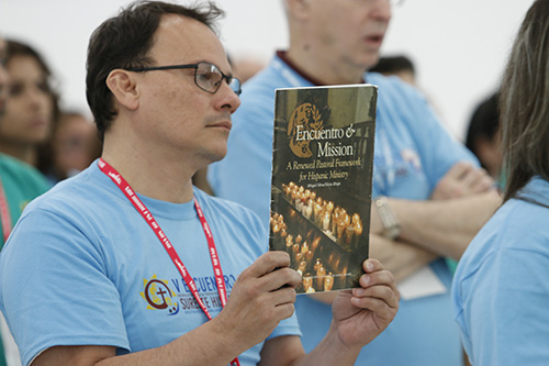 A delegate to the Southeast Regional Encuentro carries one of the documents produced by past Encuentros into Our Lady of Guadalupe Church, Doral, during the opening Mass.