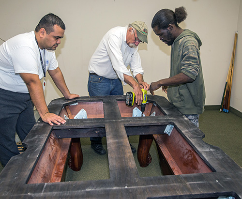 Billiards by Brandt owner Dan Brandt, center, works with Marian Center adult day training students Anthony Castellon, left, and Eric Cowherd as they assemble a billiard table at the center.