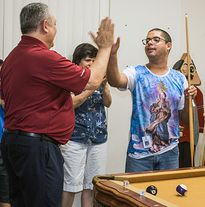 John DiToro, jugador profesional de billar, celebra con el estudiante de entrenamiento para adultos de Marian Center, Rafael Oliveira, después de un buen tiro.