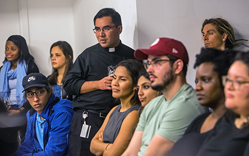 Father Phillip Tran, Catholic chaplain at the University of Miami, listens with other young adults to Theology on Tap speaker Tim Gray.