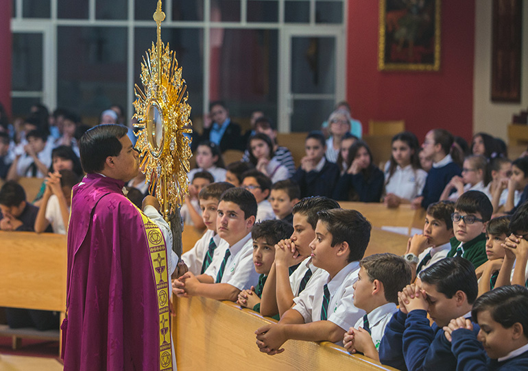 Father Elviz Gonzalez displays the monstrance to sixth graders during exposition of the Blessed Sacrament at the Focus 11 vocations rally March 1 at St. Agatha Church, Miami.